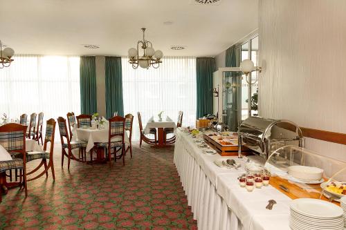a dining room with a long table with white tables and chairs at Hotel Kronprinz in Greifswald