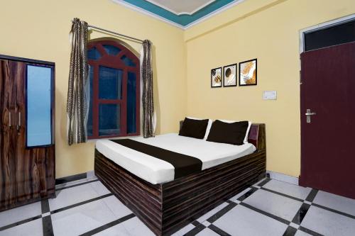 a bedroom with a bed and a window and a door at Hotel O Behror in Neemrana