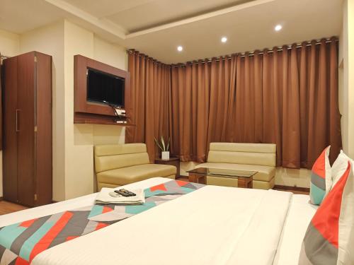 a hotel room with a bed and chairs and a tv at Loharkar Hotel in Nagpur