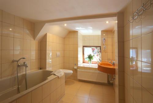 a bathroom with a tub and a toilet and a sink at Hotel Zelený Dům in Boží Dar