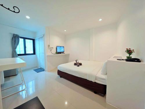 a white bedroom with a bed and a television at Ma Non Nont Hotel & Apartment in Nonthaburi