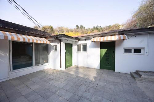 ein weißes Gebäude mit grünen Türen und einer Terrasse in der Unterkunft 5BR Family House, Myeongdong 7 minutes, Gwanghwamun 10 minutes, Namsan view, Patio in Seoul