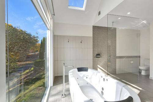 a large white bathroom with a tub and a window at Next to Bliss Luxury Guesthouse in Bright