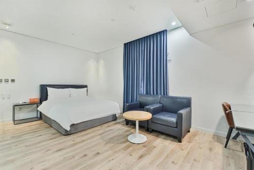 a bedroom with a bed and a couch and a chair at JB Design Hotel in Busan