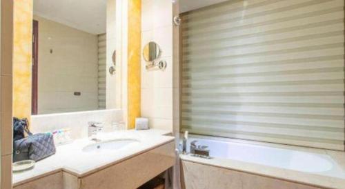 a bathroom with a sink and a tub and a mirror at Hohhot Hai Liang Plaza Hotel in Hohhot