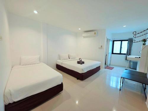 a white room with two beds and a piano at Ma Non Nont Hotel & Apartment in Nonthaburi
