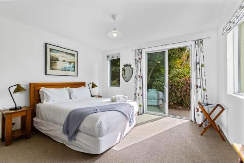 ワナカにあるLakeside Serenity Wanakaのベッドと大きな窓のある白い寝室