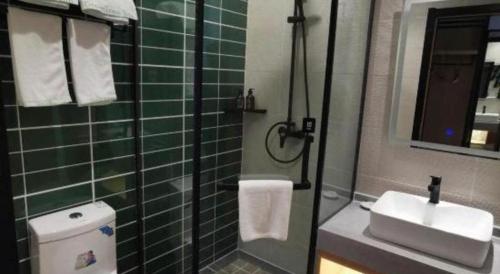 a green tiled bathroom with a toilet and a sink at GreenTree Inn Ganzhou Gan County Bus Station in Ganzhou