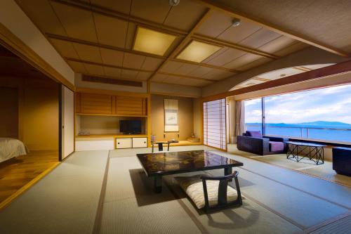 a living room with a table and a large window at Shunkeiroman Ginpaso in Gamagori