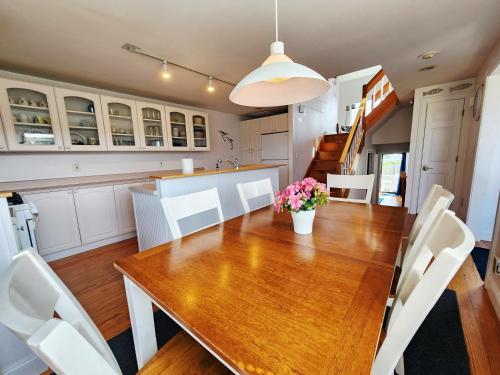 a kitchen and dining room with a wooden table and white chairs at Spacious Oceanfront 3BR Condo with Private Beach in Ideal Hyannis Location in Barnstable