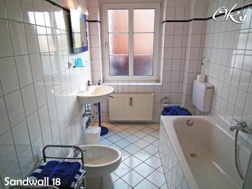 ein Badezimmer mit einem Waschbecken, einer Badewanne und einem WC in der Unterkunft Wellenblick in Wyk auf Föhr