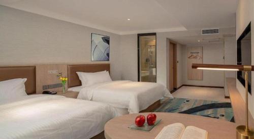 a hotel room with two beds and a table at GreenTree Inn Ganzhou Sankang Temple DaRunFa Express Hotel in Ganzhou