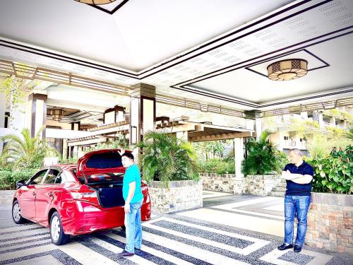two men standing in front of a car in a parking lot at Angel's Place Torre De Manila, Cozy 1BR Condo, Sunset View Near all Attractions in Manila