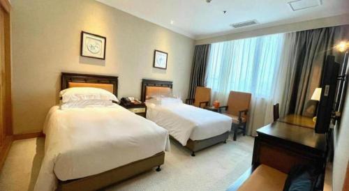 a hotel room with two beds and a desk at Xiamen Airlines Quanzhou Hotel in Quanzhou