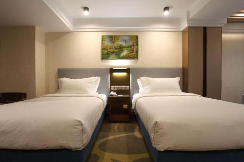 a hotel room with two beds and a painting on the wall at Dalian Bohai Pearl Hotel in Dalian
