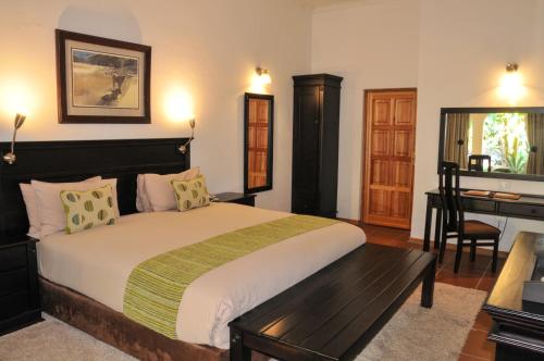 a bedroom with a large bed and a desk at Tzaneen Country Lodge in Tzaneen