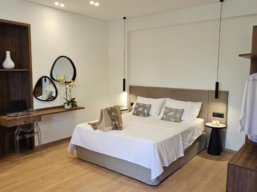 ein Schlafzimmer mit einem großen weißen Bett und einem Spiegel in der Unterkunft S & E luxury city residences in Rhodos (Stadt)