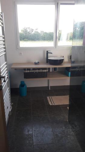 a bathroom with a counter with a sink and a window at Maison bois à la campagne in Marnay