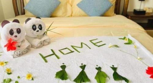 two stuffed pandas sitting on top of a bed at Da Peng Zhongzhou Hotel in Haikou