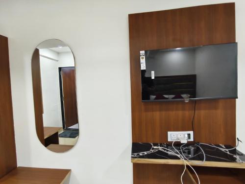 a mirror in a room with a tv on a wall at Hotel MARUTI R Drive Inn Road in Ahmedabad