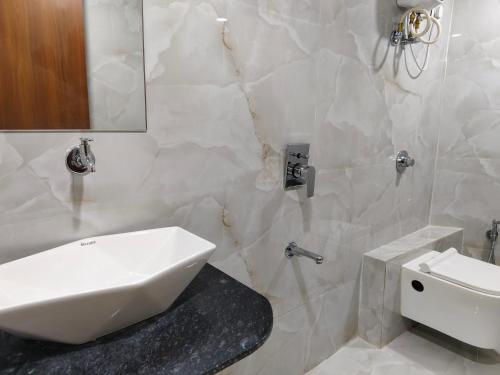 a white bathroom with a sink and a toilet at Hotel MARUTI R Drive Inn Road in Ahmedabad