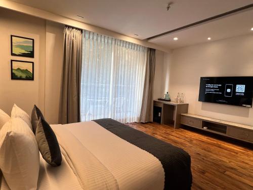 a bedroom with a large bed and a flat screen tv at Moksha Riverside Resort in Kasol