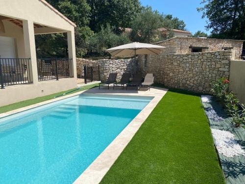 AubussarguesにあるMaison Villa Malon Sud Aubussargues Uzès Nîmes avec piscineの傘と緑の芝生があるスイミングプール