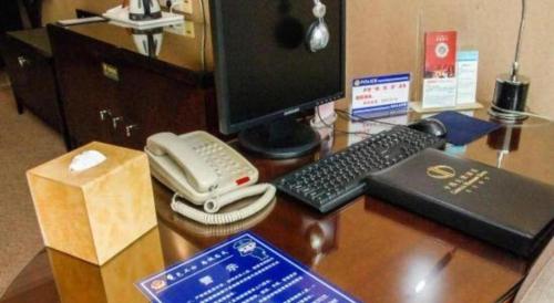 a desk with a computer and a phone on it at Chinflux Mandarin Hotel in Dongguan