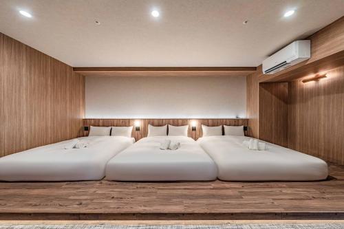 two white beds in a room with a wall at Apartment Hotel 11 Dotonbori4 in Osaka
