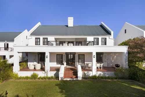 a white house with a porch and a patio at Winelands Golf Lodges 3 in Stellenbosch