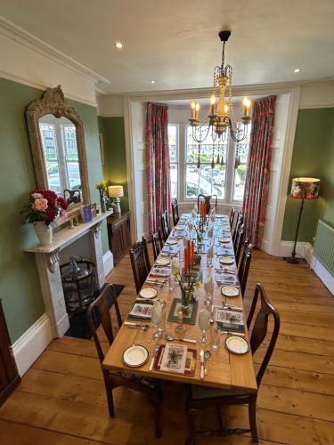 a long table in a room with chairs and a dining room at Ramsgate Retreats - Latimer House, boutique seaside holiday home for large families, groups, golf in Ramsgate