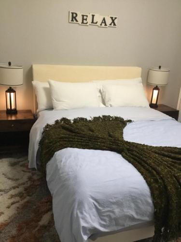 a bedroom with a bed with a green blanket on it at Almost Heaven - Cozy 2BDRM APT near Heritage Park,Spruce Meadows & Banff-SW Calgary in Calgary