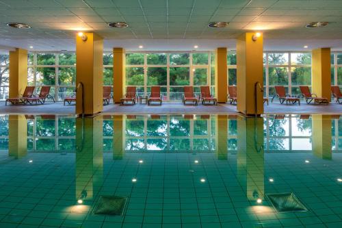 a pool in the middle of a building with chairs and tables at Hotel Aurora in Mali Lošinj