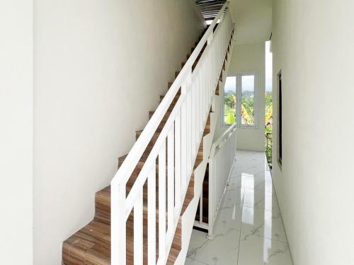 a staircase in a house with white walls at Bilqis Homestay Syariah Mitra RedDoorz in Wonosobo