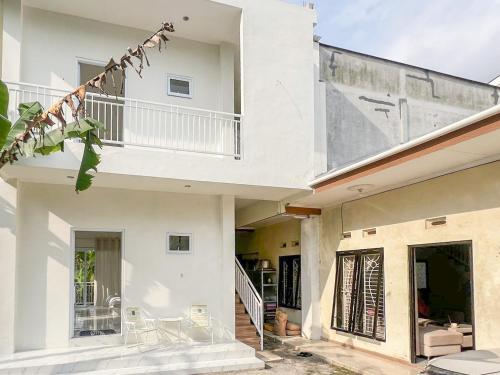 a white house with a staircase and a balcony at Bilqis Homestay Syariah Mitra RedDoorz in Wonosobo