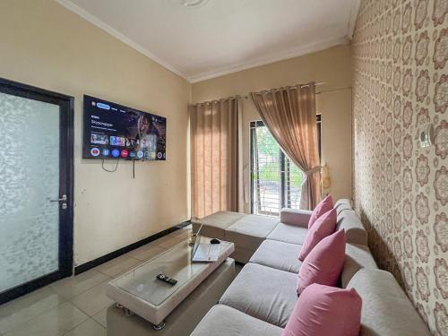 a living room with a couch and a tv at Bilqis Homestay Syariah Mitra RedDoorz in Wonosobo
