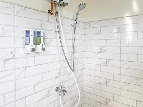 a white tiled shower with a shower head at Bilqis Homestay Syariah Mitra RedDoorz in Wonosobo