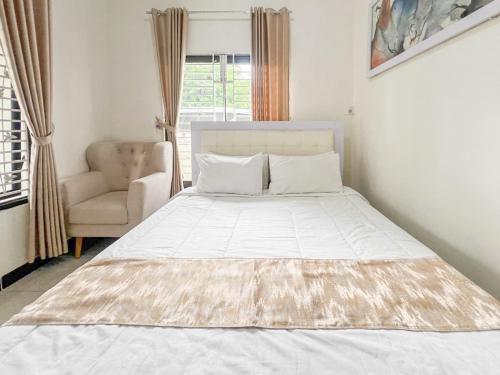 a white bed in a room with a chair and a window at Bilqis Homestay Syariah Mitra RedDoorz in Wonosobo