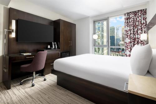 a hotel room with a bed and a desk and a window at Hilton Garden Inn New York - Times Square Central in New York