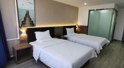 a hotel room with two beds with white sheets at 7 Days Inn Tianjin Development Zone 3rd Street Wanli in Binhai