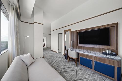 a hotel room with a couch and a flat screen tv at Hilton College Station & Conference Center in College Station