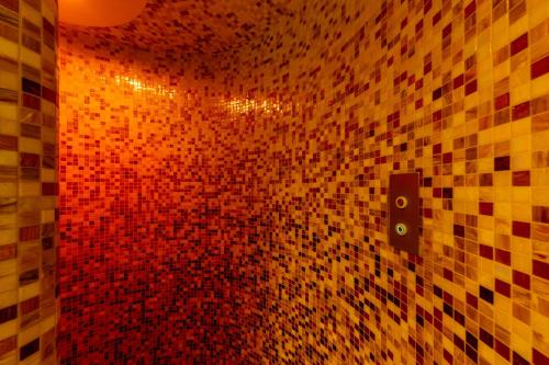 a bathroom with a tiled wall with a red light at Hotel Aurora in Mali Lošinj