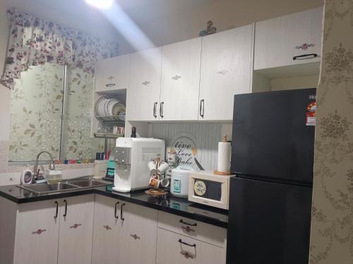 a kitchen with white cabinets and a black refrigerator at Putatan Platinium 2 Bedroom - Farah Biz Homestay in Putatan