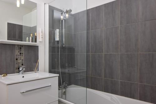 a bathroom with a shower and a tub and a sink at Zenitude Hôtel-Résidences Bordeaux Aéroport Mérignac in Mérignac