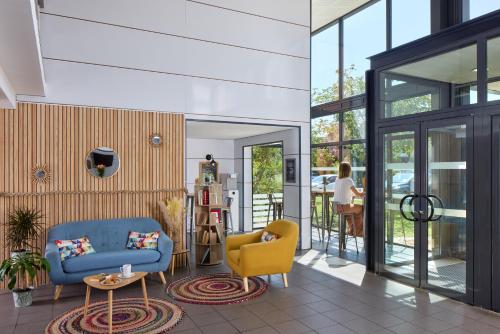 a living room with a blue couch and yellow chairs at Zenitude Hôtel-Résidences Bordeaux Aéroport Mérignac in Mérignac