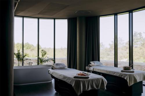 two beds in a room with a tub and windows at Hilton Swinoujscie Resort And Spa in Świnoujście