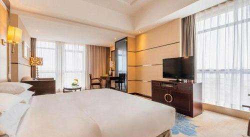 a hotel room with a large bed and a television at Gaosu New Century Hotel International Anhui in Hefei