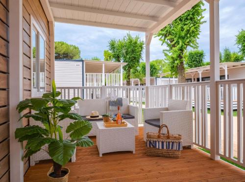 a porch with white furniture and a potted plant at Club del Sole Jesolo Family Resort in Lido di Jesolo