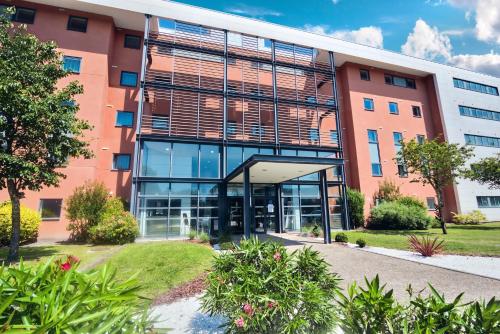 an office building with a large glass facade at Zenitude Hôtel-Résidences Bordeaux Aéroport Mérignac in Mérignac