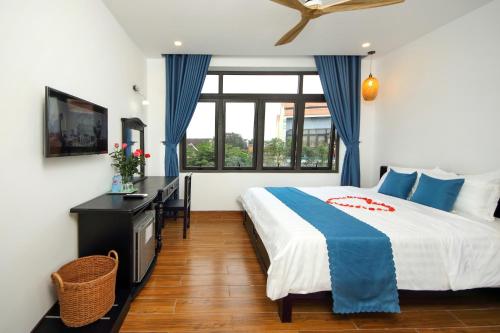 a bedroom with a bed and a desk and a window at Quynh Long Villa in Hoi An